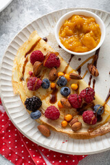 Close up of crepes with berries and nuts on plate