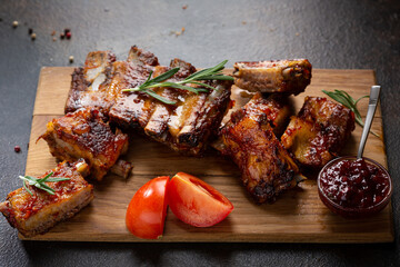 Close up of barbecue smoked ribs with red sauce on wooden cutting board