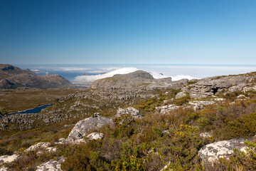 Panoramic view from top of Table Mountain to Hout Bay, Cape Town, South Africa with upcoming clouds.