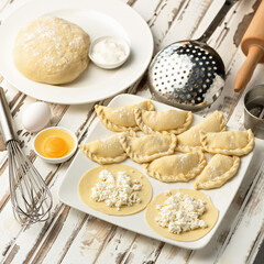 Making Sweet Dumplings with cottage cheese filling. Cooking process. Convenience Food. Slices of raw dough with filling on rustic kitchen table. Top view. Square format. Soft focus.