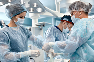 Hands of doctors in gloves during an operation, close-up of an operating nurse helping a surgeon to put on styryl gloves before the operation.