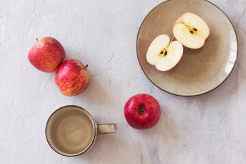 Apples and cups with plates on a grey background. Concept of healthy nutrition and vitamins. Flat lay with copy space. Horizontal orientation