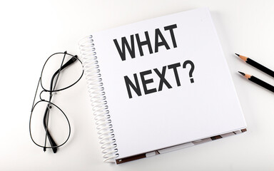 Notepad with text WHAT NEXT . White background. Business concept