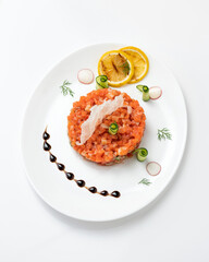 Festive salad or Snack with red sturgeon fish and vegetables. Pieces of salmon, lemon slices and cucumber rolls on white plate. Top view. Vertical format.