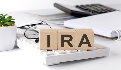 IRA written on a wooden cube on keyboard with office tools