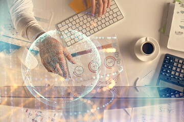 Multi exposure of man's hands typing over computer keyboard and world map hologram drawing. Top view. Technology concept.