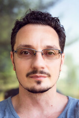 Fototapeta premium Headshot of kind and smart looking man with eyeglasses looking at camera. Young man close up portrait.