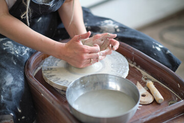 Close up female hands make dishes from clay. woman hands working on potters wheel. The master potter works in a workshop