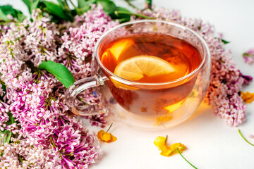 A mug of tea with lemon and lilac. Cozy romantic floral background with copy space. Flat lay.