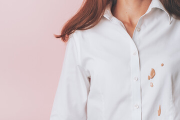 Female in a white shirt with cosmetic stains on the front, isolated on pink background. space for...