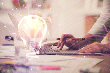 Double exposure of woman hands typing on computer and light bulb drawing. Idea concept.