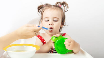 Healthy nutrition for kids. Cute baby eating vegetables in white kitchen. Infant weaning
