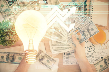 Multi exposure of bulb drawing hologram and USA dollars bills and man hands. Business Idea concept.