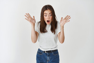 Fototapeta na wymiar Happy young woman screaming of surprise and joy, looking excited down at promo banner, standing over white background