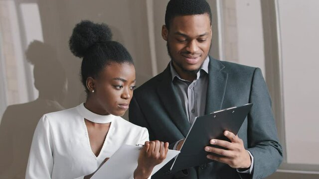 Young African businessman and businesswoman having problems with documents, discuss financial report, statistics document papers, worried about overdue debt. Giving professional consultation concept