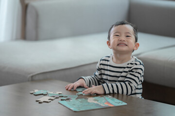 Asian little boy playing with puzzle pieces, infant early childhood education, child development concept. - obrazy, fototapety, plakaty