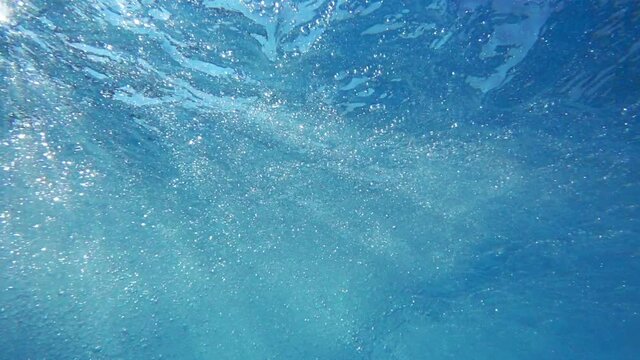 Just below the surface movie, waves, ripples, bubbles, and sun rays going through the water surface
