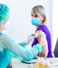 Women wearing masks getting vaccinated. Concept of coronavirus, vaccination elderly woman mask who approved covid-19 vaccination at hospital. Female doctor immunizes elderly patients against the virus