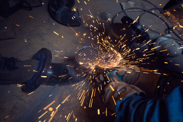 Male worker grinding  at grille pipeline elbow