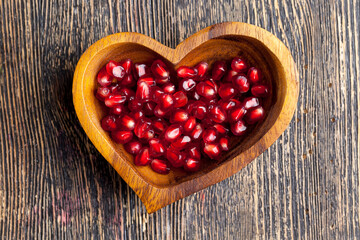 Fototapeta na wymiar fresh pomegranate seeds in a heart-shaped bowl