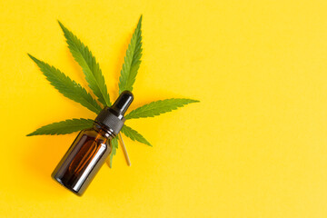 Amber glass cosmetic bottles with CBD oil and hemp leaves on a yellow background. Cosmetics CBD oil.