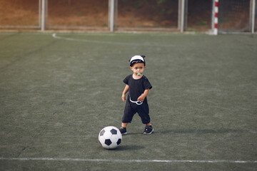 Obraz premium Little boy playing a football in a sports ground