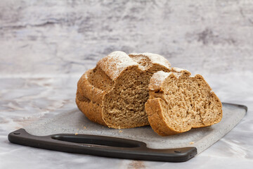 Cut loaf of bread on cutting board on kitchen desk with gray background