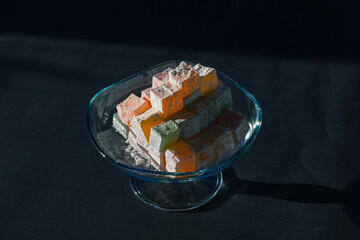 Turkish delights illuminated by sunlight on the glass bowl isolated on black background. Ramazan bayrami (eid al fitr) and Kurban bayrami (eid al adha) background photo. eid mubarak (iyi bayramlar)