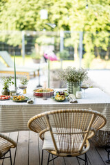 Table in the garden is covered with a tablecloth and decorated with flowers and candles with food for two persons. Summer dinner outdoor. 