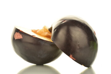 Two halves of sweet tasty dark purple plum, close-up, isolated on white.