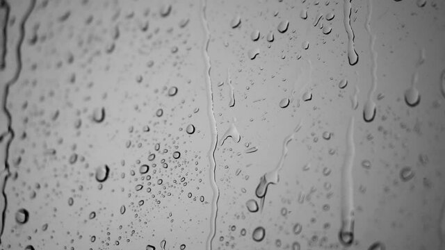 Raindrops dripping on a window glass. Heavy wind. Black and white background