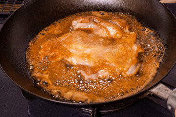 フライパンの上で調理中の日本の鶏モモ肉の照り焼き
