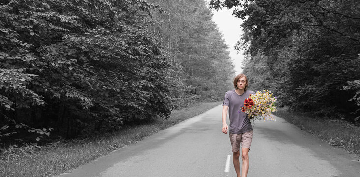 A young guy with flowers on a forest road