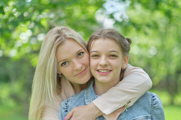 Fototapeta na wymiar happy mother with her daughter hugging a teenager in the summer. Caring happy mother enjoy day with teenage girl child, laugh have fun. Mother giving her daughter advice.
