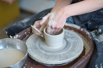 Close up female hands make dishes from clay. woman hands working on potters wheel. The master potter works in a workshop