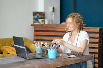 artisan pottery tutor in art studio. woman ceramist teaches an online lesson or leads a video master class on creating ceramic products