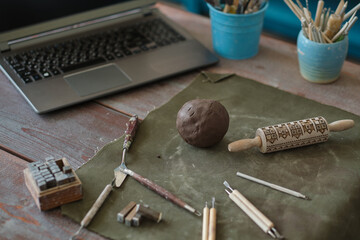 clay and tools are on the table in front of the laptop. ceramics online training concept. video tutorials for hobbies. Pottery tools
