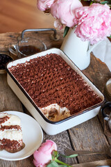 Homemade tiramisu. Peonies, coffee, blueberries. Wooden background. Side view.