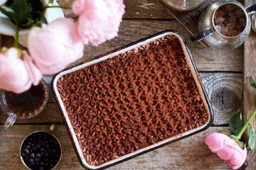 Homemade tiramisu. Peonies, coffee, blueberries. Wooden background. Top view.