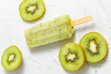 Frozen kiwi fruit ice or sorbet or popsicle with slices on white cement background