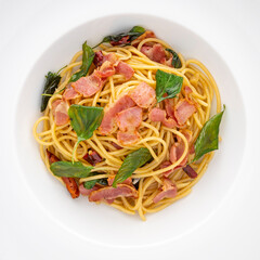 top view shot of Spaghetti Pasta with Dried Chilli, Garlic, Sweet Basil and Bacon in white ceramic plate texture background, square ratio