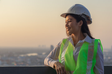 worker woman wearing hard hat helmet standing on rooftop look at downtown