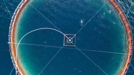 Salmon fish farming in Norway sea. Food industry, traditional craft production, environmental conservation. Aerial view of round mesh for growing and catching fish in arctic water surrounded by fjords