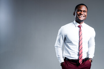 Cheerful african american businessman in shirt and tie with hands in pockets smiling