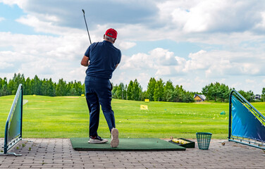Male golf player on professional golf course. Golfer with golf club taking a shot