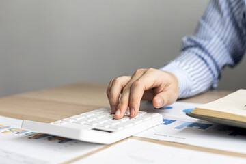 Female auditor pressing white calculator, she is a private company auditor, she is reviewing numbers of company financial statements before presenting them to senior management. Audit concept.