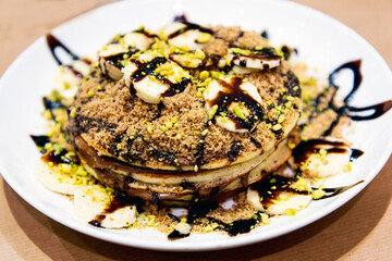 Delicious homemade pancakes with banana slices, hazelnuts and Greek pralines for a sweet breakfast