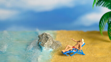Miniature people toy figure photography. A Men relaxing on beach chair when daylight at seaside.