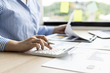 A female financier is reviewing company financial documents, monthly financial statement summary from the finance department. The concept of managing the company's finances for accuracy and growth.