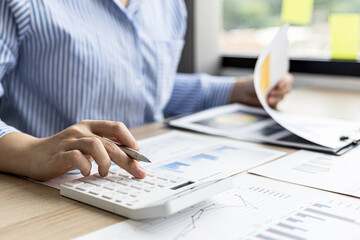 A female financier is reviewing company financial documents, monthly financial statement summary from the finance department. The concept of managing the company's finances for accuracy and growth.